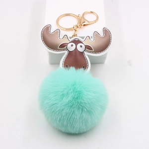 Détail du pompon en fourrure vert menthe avec charme d'élan en cuir et fermoir doré chic