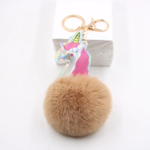 Close-up of holographic unicorn keychain with fluffy brown faux fur pom pom and gold ring