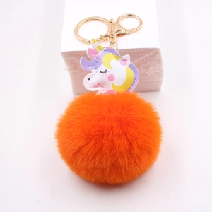Nahaufnahme von Einhorn-Schlüsselanhänger mit orangefarbenem Plüschball und Goldclip
