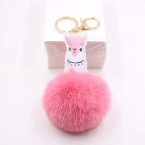 Détail du porte-clés pompon rose avec patch alpaga en cuir et fermoir mousqueton doré