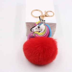 Macro shot of colorful unicorn keychain with large red plush ball and golden metal ring