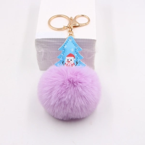 Detail of lavender faux fur pom pom keychain with blue snowman leather tag and gold hardware
