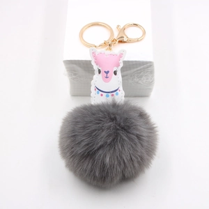 Détail du patch en cuir alpaga et du pompon en fausse fourrure grise du porte-clé
