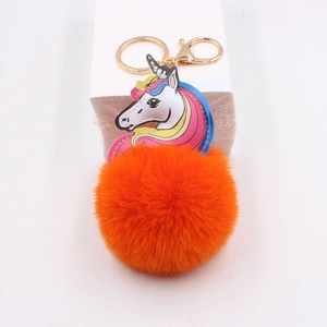 Detail of colorful unicorn keychain with orange faux fur pompom and golden metal lobster clasp