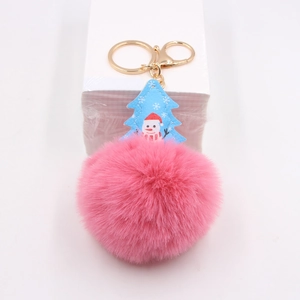 Detail view of a fluffy pink pompom keychain with a blue snowman pattern leather charm
