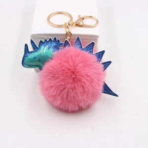 Porte-clés dinosaure en pompon rose avec détails irisés et anneau doré brillant