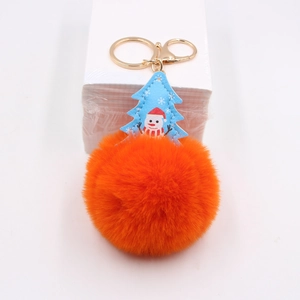 Close-up of fluffy orange faux fur pom pom with blue snowman charm and golden metal clasp