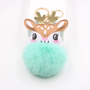 Detail of mint green faux fur pompom keychain with golden glitter reindeer antlers
