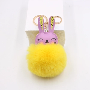 Close-up of cute purple rabbit head and bright yellow fluffy pompom keychain detail