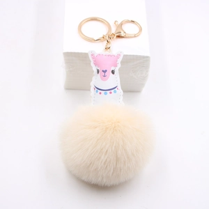 Détail du charme d'alpaga en cuir rose avec pompon beige et fermoir mousqueton doré