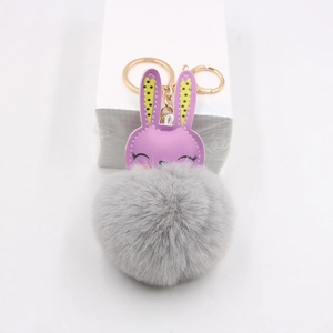 Close-up of cute purple leather rabbit with fluffy grey fur ball pompom keychain