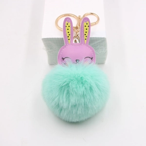 Close-up of a purple bunny plush keychain with mint green fur pompom and golden ring