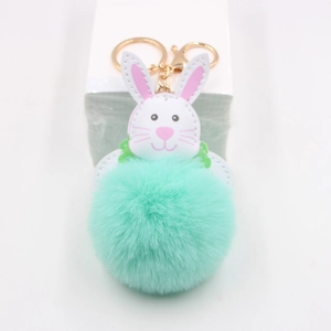 Close-up of mint green fluffy fur ball keychain with white rabbit head and gold hardware