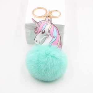Close-up of mint green unicorn pompom keychain with golden metal ring and lobster clasp
