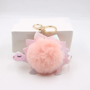 Close-up of pink iridescent dinosaur keychain with soft faux fur pompom and gold clasp