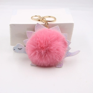 Detailed view of pink plush pom pom dinosaur keychain with iridescent leather scales and gold ring