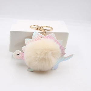 Cute cartoon dinosaur keychain with colorful fish scale texture and fluffy faux fur pompom