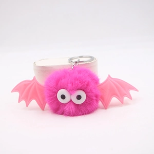 Detailed close-up of fluffy pink pom-pom bat keychain with cute wings and big eyes