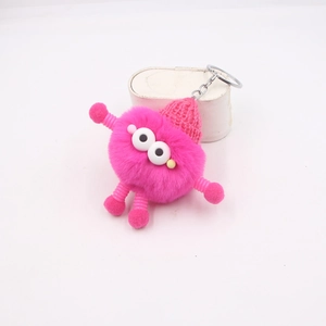Détail du porte-clés monstre rose pelucheux avec bonnet tricoté et pattes spirales