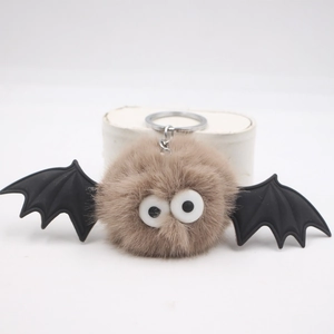 Macro shot of fuzzy Halloween bat plush keychain with googly eyes and black wings