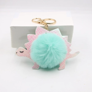 Detail of pink dinosaur plush keychain with crocodile texture and mint green pompom