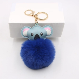 Close-up of blue leather koala pendant and fluffy faux fur pompom keychain with gold ring