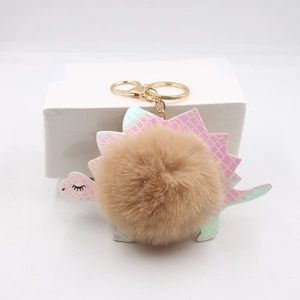 Detail of cute dinosaur plush pom-pom keychain with golden metal ring and lobster clasp
