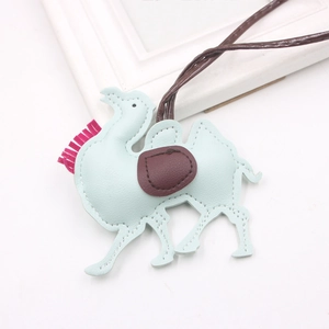 Close-up of light blue leather camel bag charm with red saddle and pink tassels