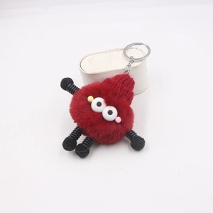 Détail d'un porte-clés monstre en peluche rouge avec membres à ressort et gros yeux