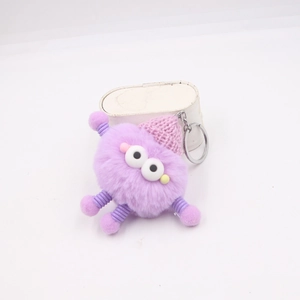 Porte-clés monstre en peluche violette avec membres à ressort et bonnet rose sur fond blanc