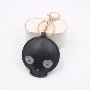 Creative black skull PU leather keychain with gold hardware on white background