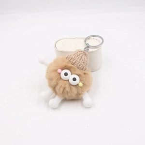 Détail du porte-clés monstre en peluche avec fourrure marron, bonnet tricoté et yeux