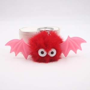 Close-up of fluffy red bat plush keychain with pink wings and large funny eyes detail