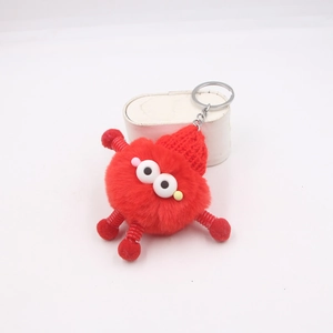 Détail d'un monstre en peluche rouge avec membres à ressort et porte-clés métallique
