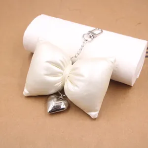 Elegant cream satin bow keychain with a silver metal heart pendant for bags and keys