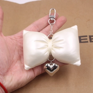 Chic cream faux leather bow keychain with a polished silver heart pendant and metal clasp