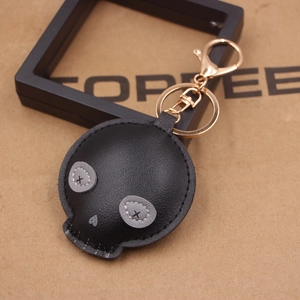 Macro detail of black leather skull keychain with X-stitched eyes and golden metal clip