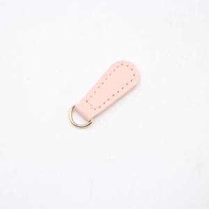 Macro detail of teardrop pink leather pendant with a gold D-ring for DIY accessories
