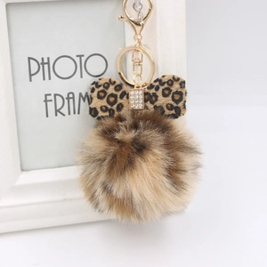 Detail of leopard print bow and fluffy pompom keychain with golden lobster clasp