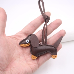 Detailed close-up of a brown leather dachshund keychain pendant held in a person's hand