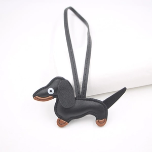 Detail view of a handcrafted black and brown leather dachshund puppy keychain with strap