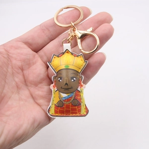 Cartoon monk leather keychain with gold lobster clasp held in hand on white background