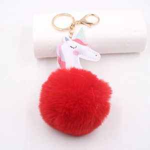 Close-up of fluffy red pompom unicorn keychain with gold metal hardware and hook