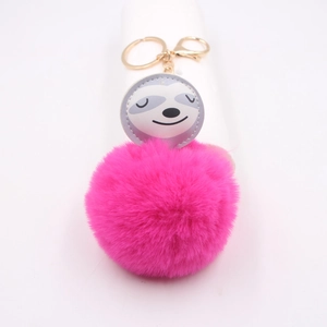 Détail du pompon en fausse fourrure rose vif et breloque paresseux sur porte-clés doré