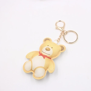Cartoon bear keychain with red bow tie and golden metal ring on white background