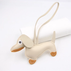 Detail of cream leather dachshund charm showing lychee texture and fine brown stitching
