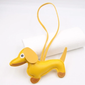 Detail of yellow leather dachshund bag charm with fine brown stitching and hanging strap