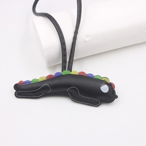 Detail of handmade black leather animal charm with colorful sawtooth accents on white background