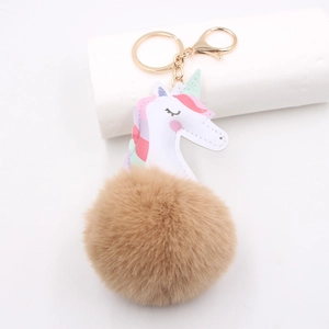 Detail of unicorn keychain with gold lobster clasp and a fluffy brown faux fur pom pom