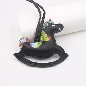 Detail of a black leather rocking horse bag charm with vibrant graffiti pattern accents